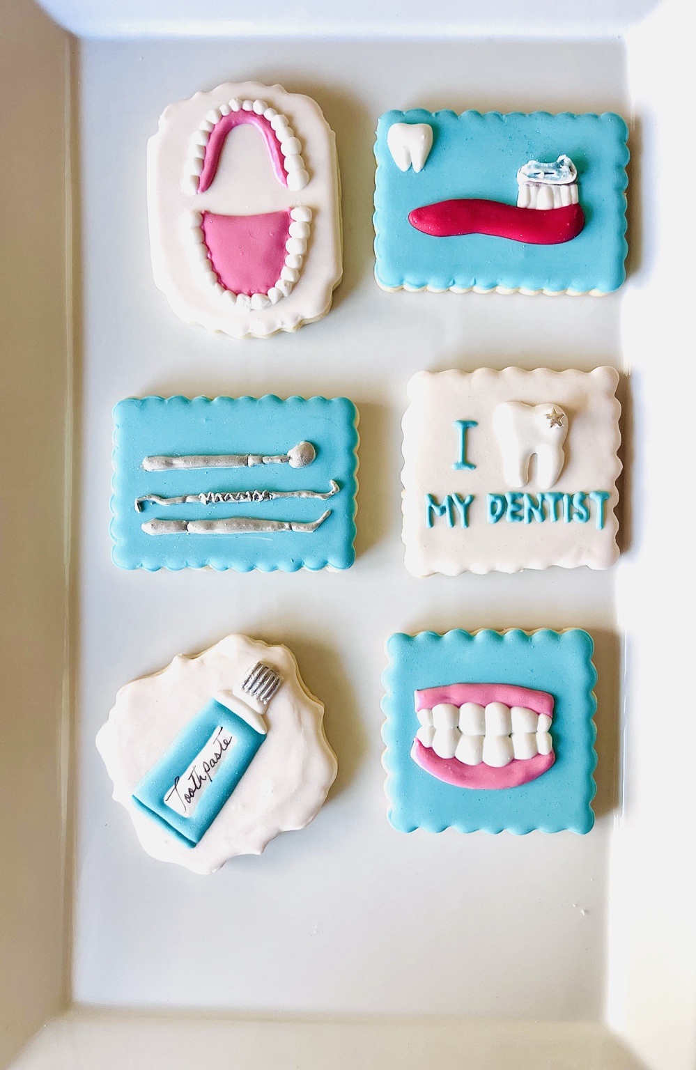 Blue and white dental-themed cookies featuring teeth, dental tools, toothpaste, and a toothbrush