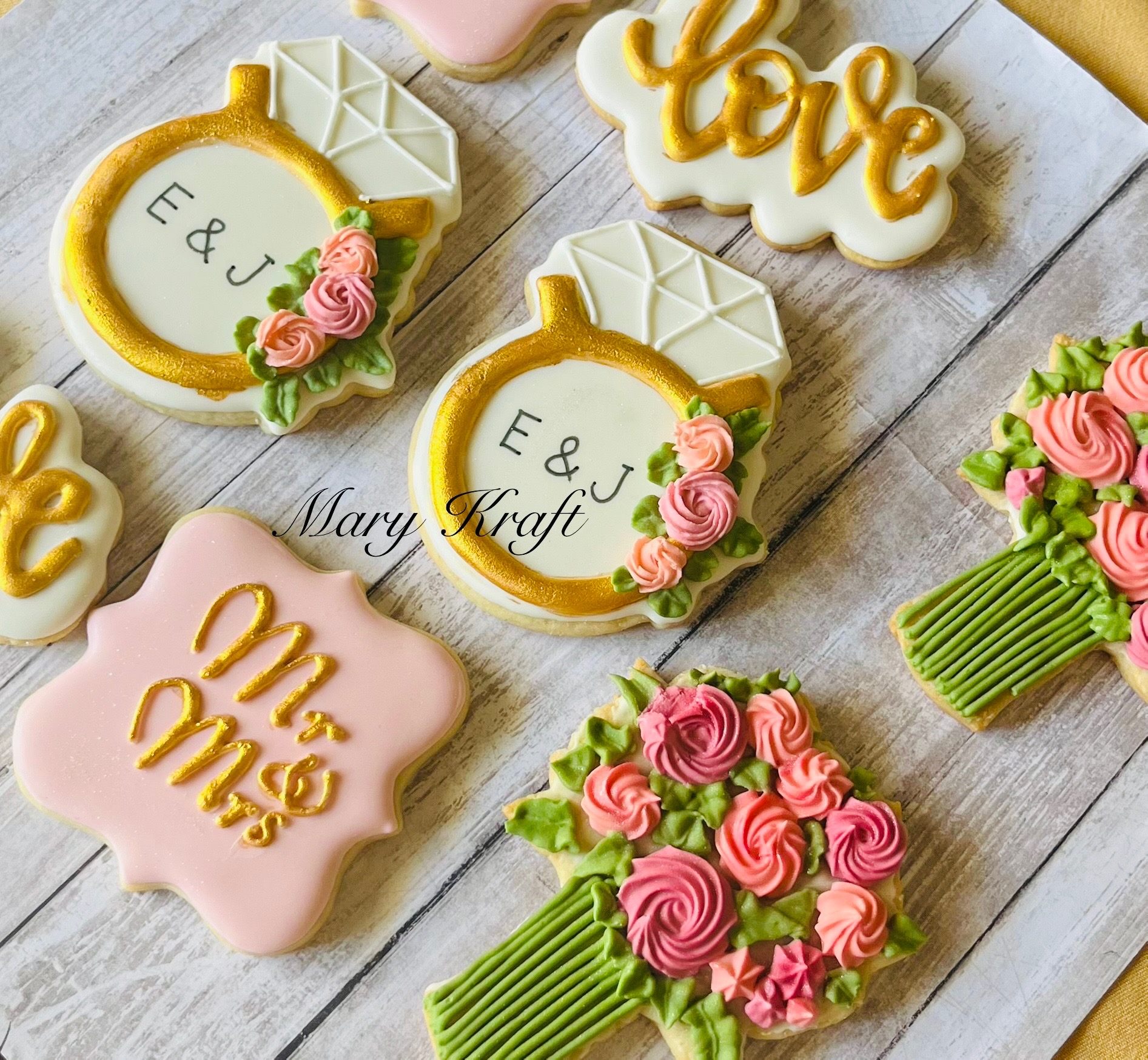 Pink, white, and gold wedding cookies with rings and floral bouquets